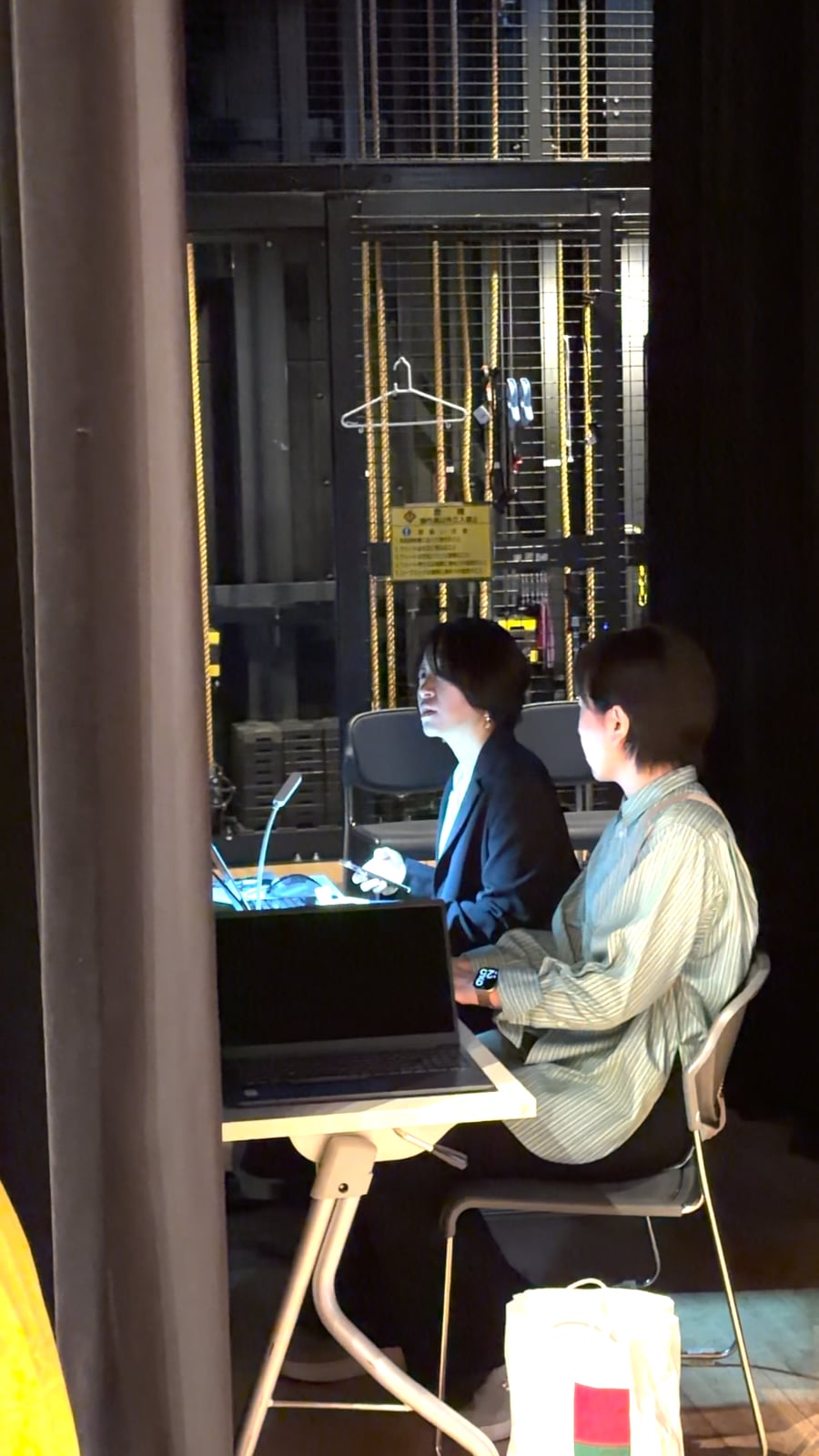 イベント会場の舞台裏でパソコンとスマートフォンを確認する溝口みき