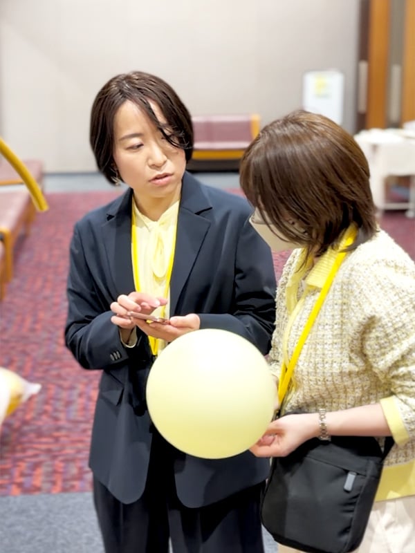 イベント会場でスマートフォンを見ながら運営メンバーと確認する溝口みき