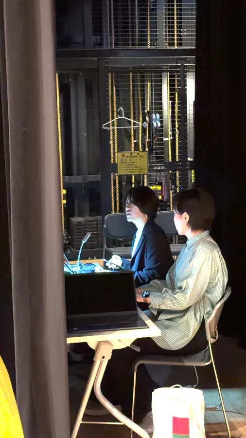 舞台裏でスタッフと進行を確認する様子